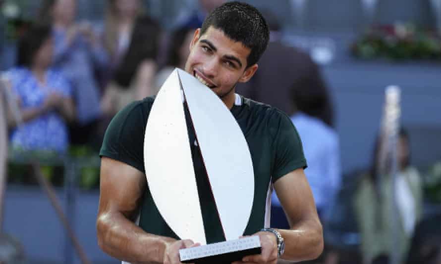 Carlos Alcaraz bites the trophy after winning Madrid Open in May.