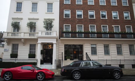 A red Ferrari and a black Rolls-Royce stand parked outside properties on Eaton Place. Kensington