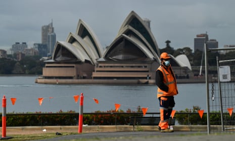 Construction worker stands near fencing with Sydney Opera house in background