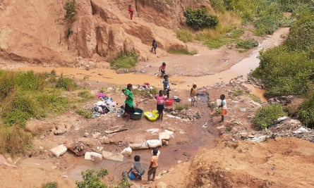 Women washing clothing beside a stream.