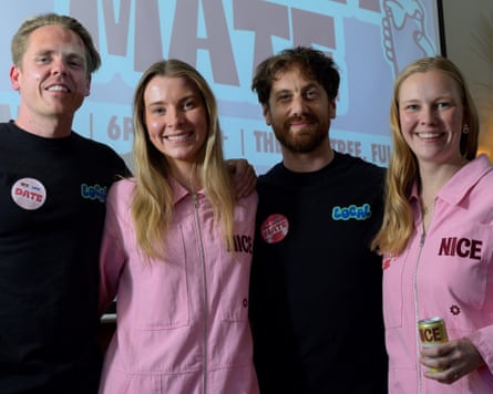 Two women in a pink jumpsuits standing with two men in black T-shirts in a pub in London