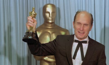 Robert Duvall holding an Oscar in front of a lifesize Oscar statue