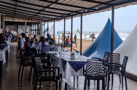 People sit in a dining area next to the beach