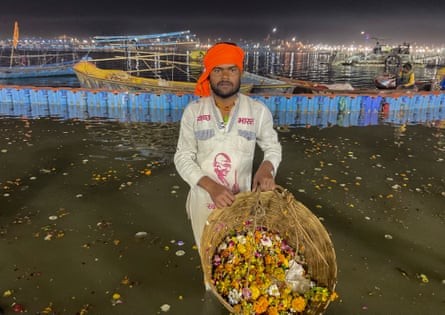 A man holds a basket of rubbish, most of which is flowers