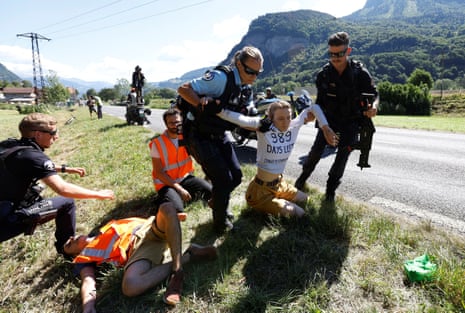 Police officers remove protestors from the road after they blocked the route during stage 10.