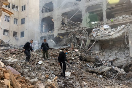Three men climb over the rubble of a destroyed building and synagogue, after a missile attack in Tehran