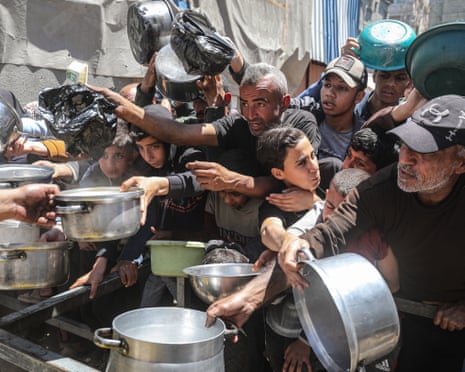 A charity distributes meals to Palestinians in the Nuseirat refugee camp in Gaza City as food shortages continue amid Israel’s blockade and restrictions on aid entry
