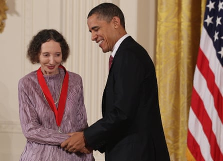 Obama holds Oates’s hand. She is wearing the medal on a red lanyard, the US flag is to the side of them