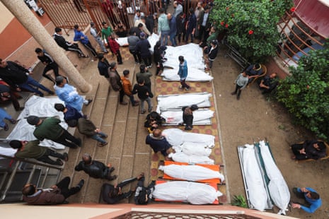People stand at Nasser hospital near the bodies of Palestinians who were killed during Israeli strikes on Ma’an school east of Khan Younis.
