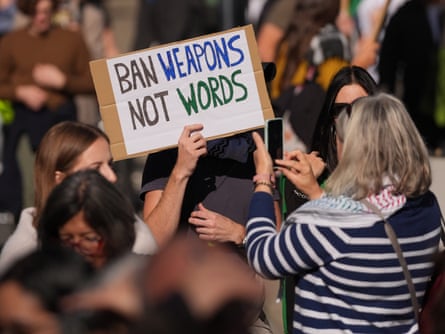 A person holds a sign reading ‘Ban weapons not words’