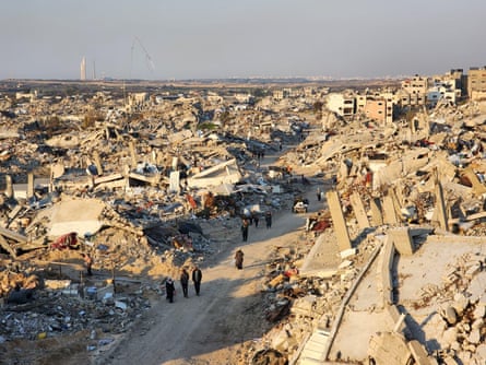 People walk among destroyed buildings.
