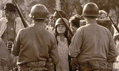 A young female protester wearing a helmet faces down helmeted and armed police officers at an anti-Vietnam war demonstration outside the 1968 Democratic national convention in Chicago.