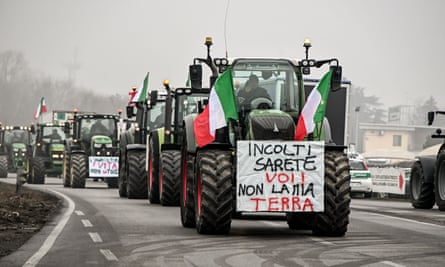 Tractors displaying placards and Italian flags drive down a road