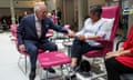 Prince Charles sits on a chair and holds hands with a woman sat next to him
