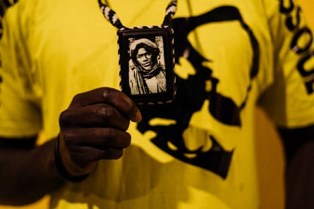 An African man holds an old black and white photo of a man in a turban