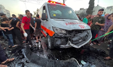 فلسطينيون يتفقدون الأضرار التي لحقت بقافلة سيارات الإسعاف عند مدخل مستشفى الشفاء في مدينة غزة يوم الجمعة.