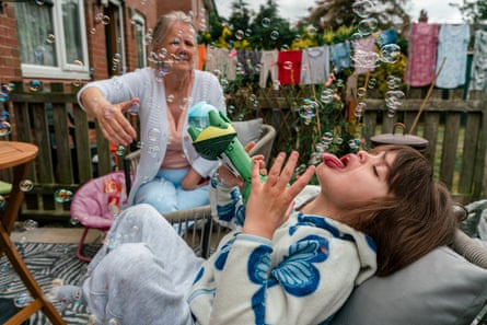 A nine-year-old girl playing with bubbles in a garden as her grandmother watches