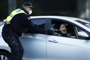 A woman tries to avoid police in her car, outside public housing towers on Racecourse Road in Flemington. Police are enforcing a lockdown at public housing towers in Melbourne after Victoria recorded 108 new coronavirus cases, forcing the lockdown of nine public housing towers and two more Melbourne postcodes