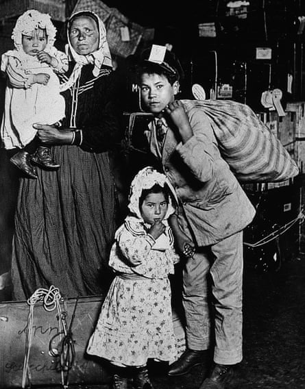 An Italian immigrant woman stands with her three children in front of steamer trunks at the Ellis Island processing center, New York City, 1905