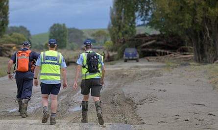 Police walk up Dartmoore Road on foot to check houses and search for bodies in Napier, New Zealand.