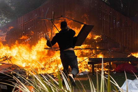 A man throws a desk on to a fire that rages on the grounds in front of New Zealand’s parliament