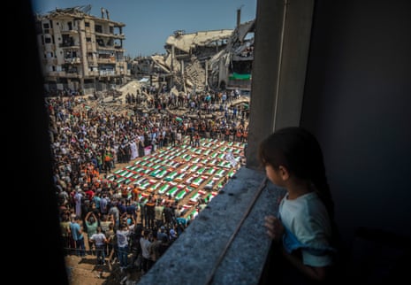 A girl watches the funeral from a window.