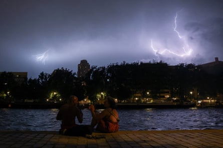 People sit on the banks of the Bassin de la Villette in Paris during a storm.
