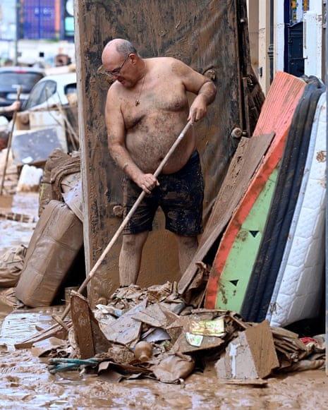 A man tries to clean his house as the street is covered in mud on October 31, 2024 after flash floods affected La Torre, in Valencia, eastern Spain.