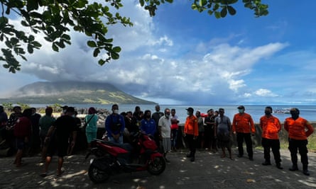 Members of the National Search and Rescue Agency looking at smoke and ash erupting from Mount Ruang, as seen from Sitaro, Indonesia on 17 April