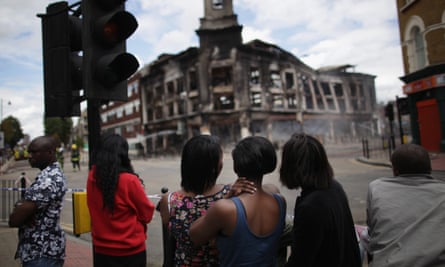 Residents watch as a building burns after riots on Tottenham High Road on 7 August 2011.