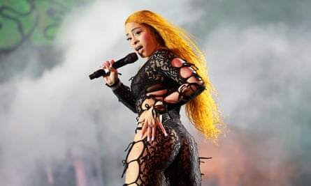 a woman in a black lace jumpsuit with long orange hair
