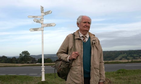Jim Broadbent standing by a finger post with a rucksack slung over his shoulder