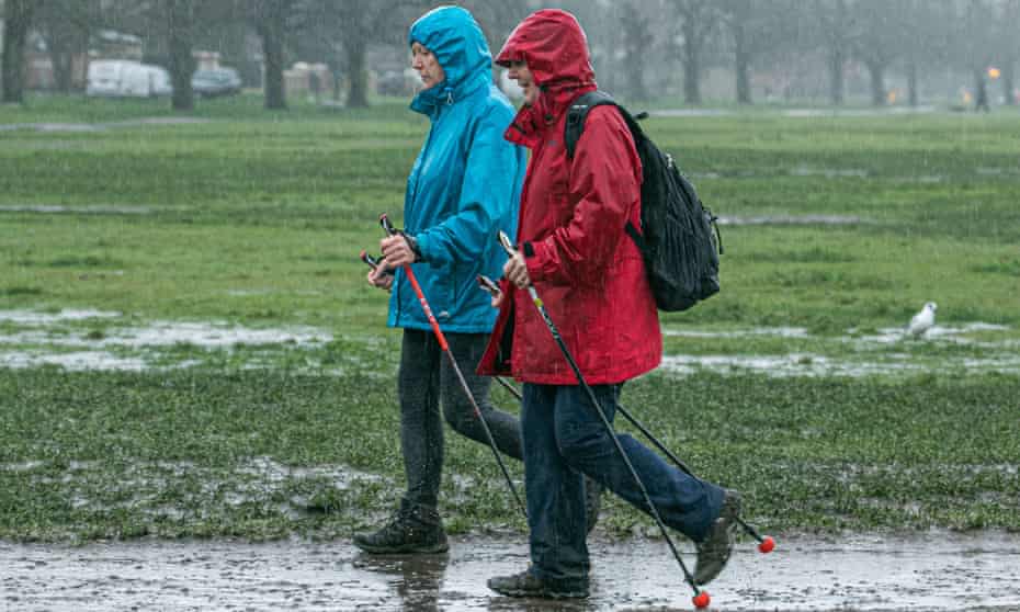 two women walking in heavy rain on Wimbledon common