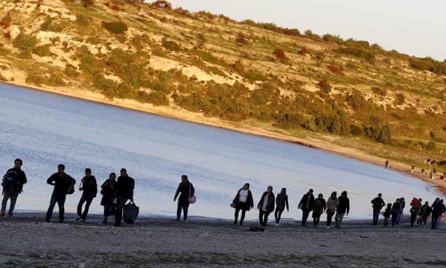 Refugees walk along a beach in Izmir province, Turkey.
