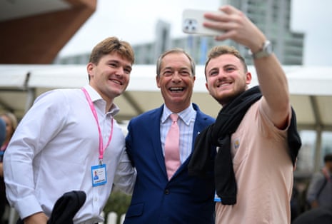 Nigel Farage posing for a selfie with two attendees at the Tory conference in Manchester.