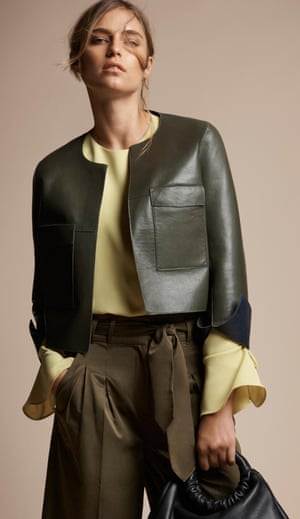 A model wears a leather jacket, blouse and trousers in earthy tones.