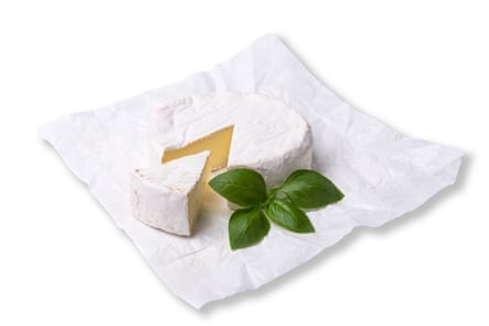 Head of camembert or brie cheese with a sprig of green basil. Isolated on white background.Head of tasty camembert or brie cheese with a sprig of green basil. Isolated on white background.