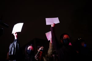 Protesters march while holding blank white pieces of paper.