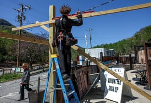 A person up a ladder assembling the wooden frame of a building
