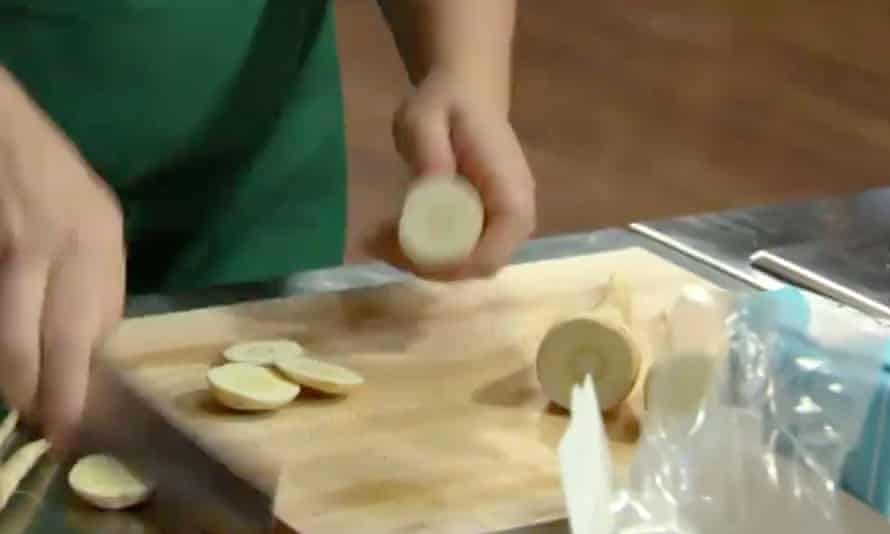 hands chopping parsnips on a cutting board