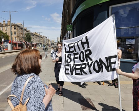 People on the street hold up a sign that says: 'Leith is for everyone'