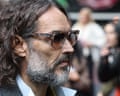 Brand, with curly hair, grey beard and tinted glasses, seen in profile arriving at court