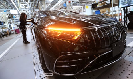 A Mercedes-Benz employee checks an electric vehicle on the assembly line at its plant in Sindelfingen, Germany