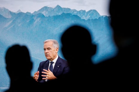 Canada's PM Mark Carney gestures while speaking, seen past silhouetted audience members with a mountain backdrop