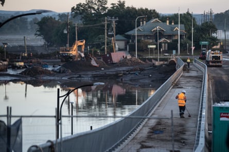 Workers clear debris on Saturday from the new Windsor Bridge, which was under water during the recent floods.