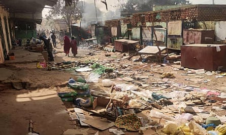 People walking among scattered objects in the market of Geneina