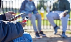 Blurred picture of teenagers boys one with mobile phone vaping and drinking