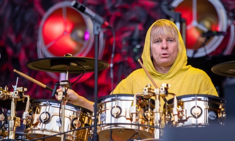 Zak Starkey dressed in a yellow hoodie, sitting behind his drum kit