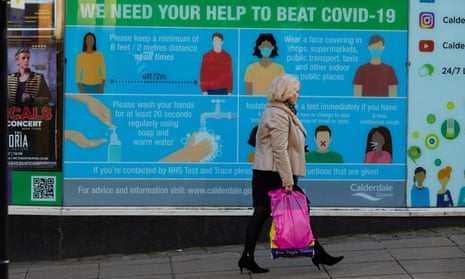 Pedestrians passing a Covid-19 information sign in Halifax, West Yorkshire. 