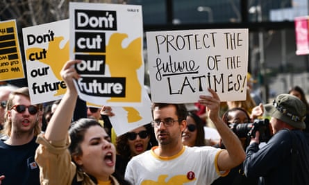people hold up signs saying ‘don’t cut our future’ and ‘protect the future of the la times’